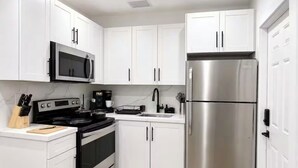 A modern kitchen with white cabinets, stainless steel appliances, and a black stove. - 3bed Near Beach, Wynwood Design District, Brickell (Miami)
