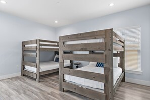 A room with two bunk beds, a small table, and a window with blinds. - Solara Sanctuary | Golf Cart, Spa, & Billiards (Miramar Beach)