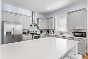 Et moderne køkken med rustfrie hvidevarer, en stor ø og et flisebeklædt backsplash.