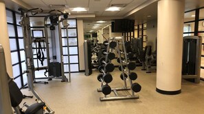Et fitnessrum med forskellig træningsudstyr, herunder styrkemaskiner og håndvægte.