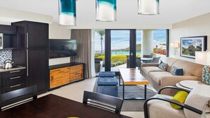 Uma sala de estar moderna com televisão, sofá e área de jantar, destacando uma grande janela com vista para o exterior.