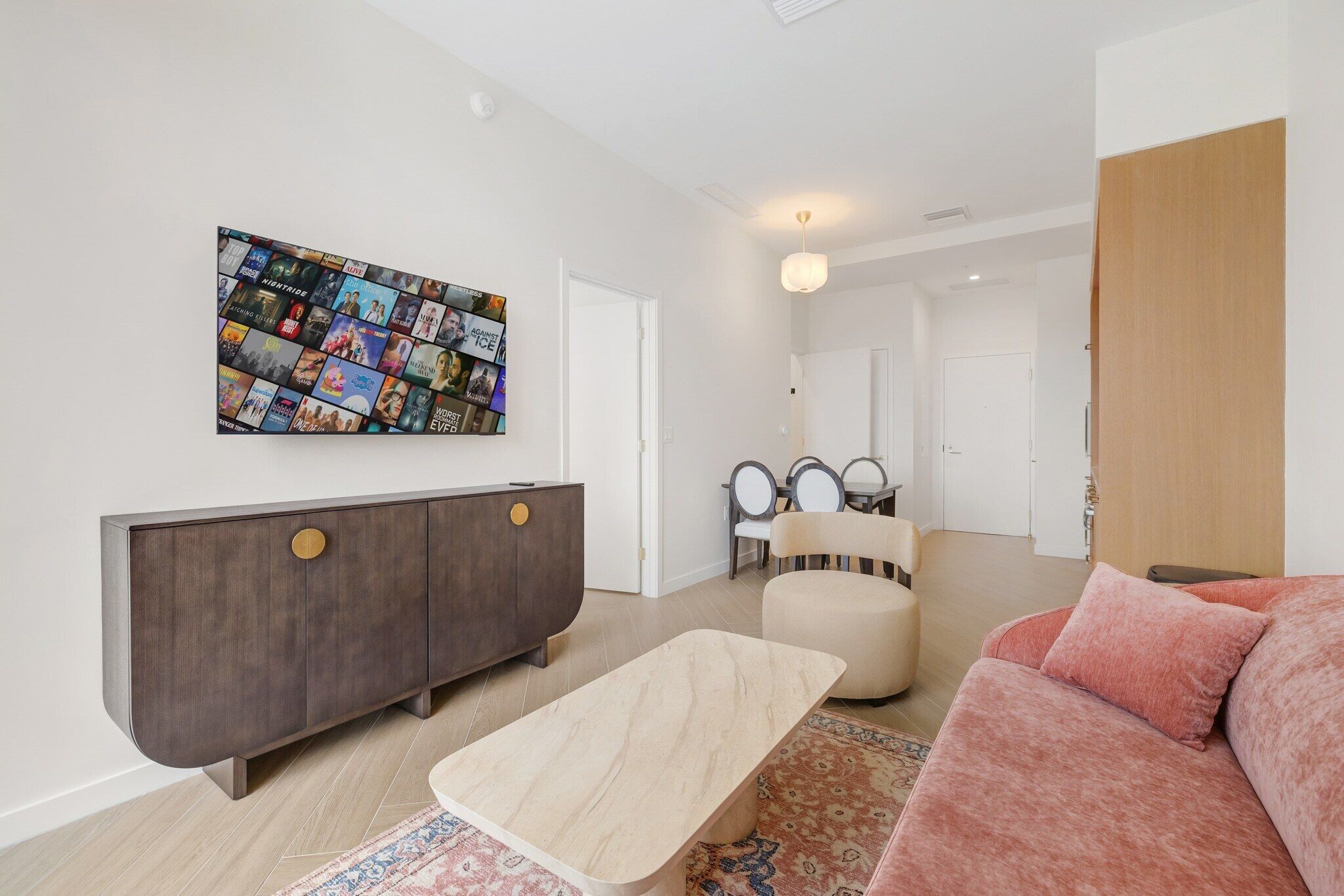Un salon moderne agrémenté d’une grande œuvre d’art murale, d’un meuble en bois foncé, d’un canapé beige et d’un tapis à motifs.
