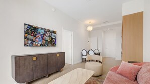 A modern living room with a large wall art piece, a dark wood cabinet, a beige sofa, and a patterned rug. - Chic Miami Apt Pool Gym & Sleeps 4 (Miami)