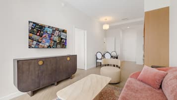 Un salon moderne agrémenté d’une grande œuvre d’art murale, d’un meuble en bois foncé, d’un canapé beige et d’un tapis à motifs.