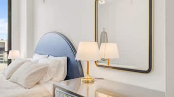 Une chambre d’hôtel avec un lit, deux lampes de chevet, un miroir et une commode.