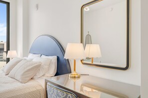 A hotel room with a bed, two bedside lamps, a mirror, and a dresser. - Chic Miami Apt Pool Gym & Sleeps 4 (Miami)