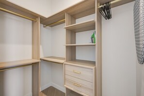 A walk-in closet with open shelving, a hanging rod, and a drawer unit. - Chic Miami Apt Pool Gym & Sleeps 4 (Miami)