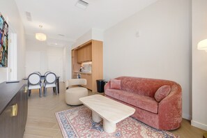 A modern living room with a sofa, a coffee table, and a dining area with chairs and a table. - Chic Miami Apt Pool Gym & Sleeps 4 (Miami)