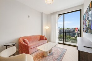 A modern living room with a sofa, a coffee table, and a view of the city through large windows. - Chic Miami Apt Pool Gym & Sleeps 4 (Miami)