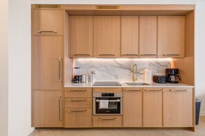 Una cocina moderna con armarios de madera, horno empotrado, pileta y cafetera.