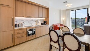 A modern kitchen with wooden cabinets, a marble countertop, and a dining area with a table and chairs. - Chic Miami Apt Pool Gym & Sleeps 4 (Miami)