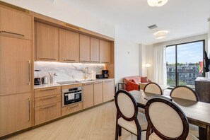 A modern kitchen with wooden cabinets, a marble countertop, and a dining area with a table and chairs. - Chic Miami Apt Pool Gym & Sleeps 4 (Miami)