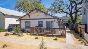 A single-story house with a front porch, a small yard, and a tree in the background. - Paso on Oak by Avantstay Cottage-style Home + Full Kitchen + Front Deck Near Downtown (Paso Robles)