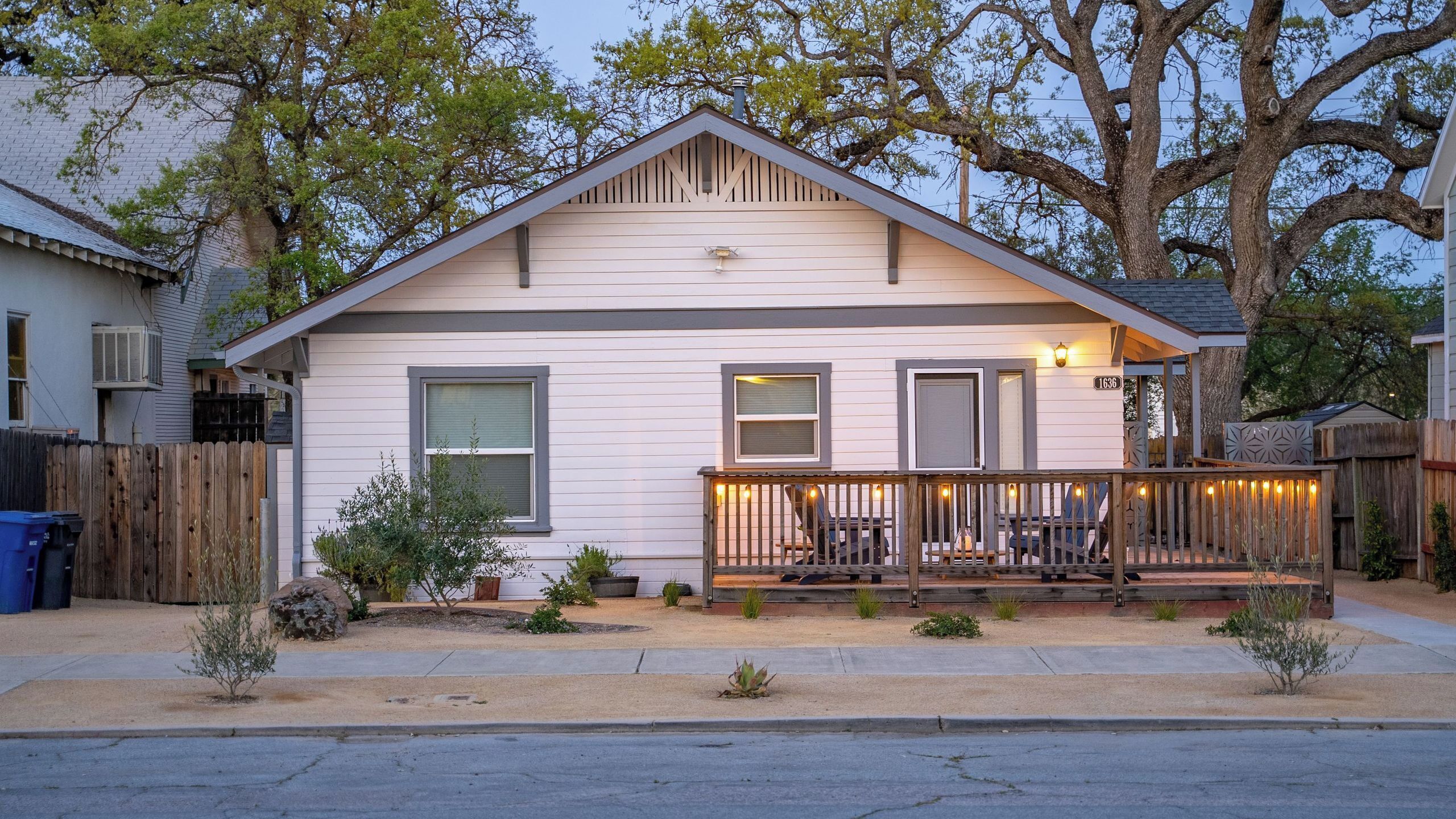 A single-story house with a front porch, a small garden, and a wooden fence.