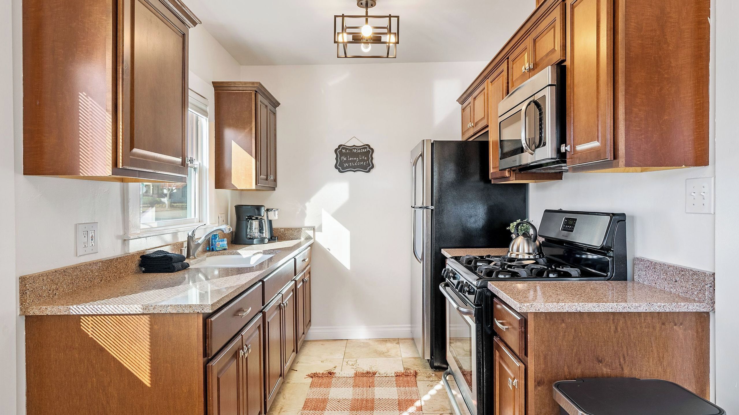 A kitchen with wooden cabinets, a stainless steel refrigerator, a stove, and a microwave.