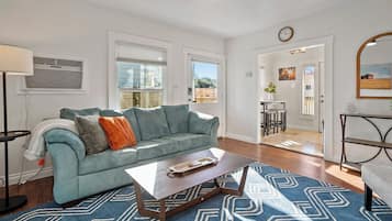 Un salon avec un canapé, une table basse et un tapis à motifs.