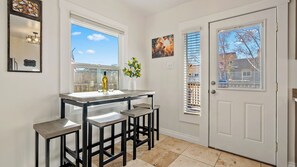 A kitchen with a bar area, a white door, and a window with blinds. - Paso on Oak by Avantstay Cottage-style Home + Full Kitchen + Front Deck Near Downtown (Paso Robles)