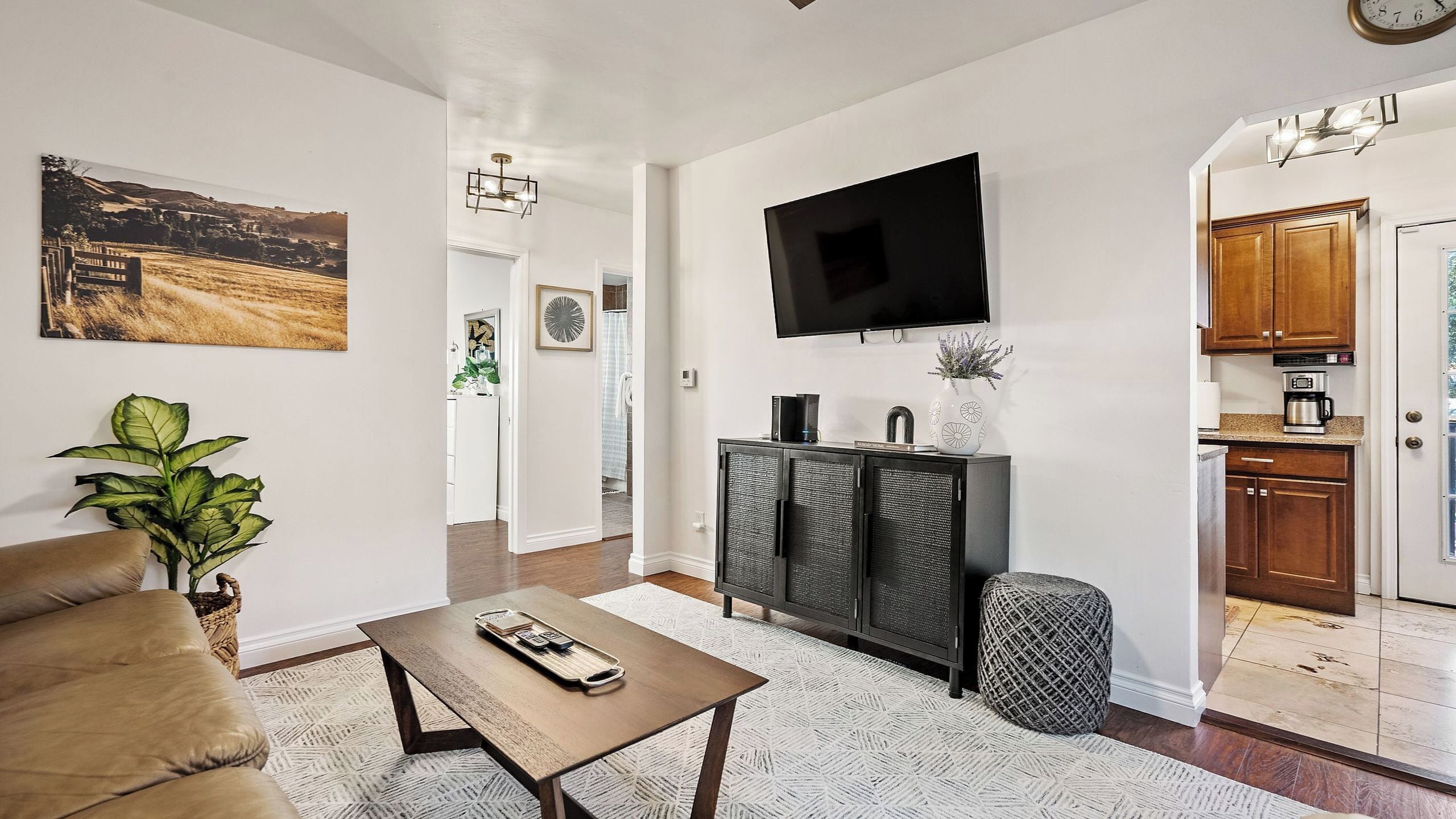 A living room with a sofa, coffee table, and a TV mounted on the wall.