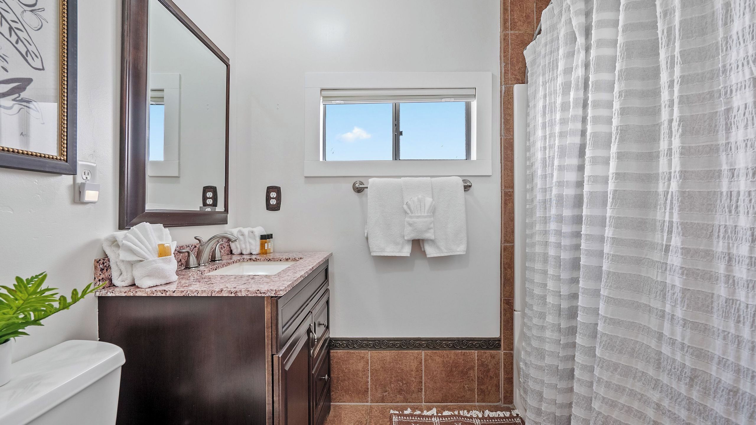 A bathroom with a sink, mirror, towel rack, and a window.