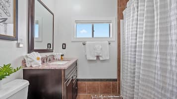 A bathroom with a sink, mirror, towel rack, and a window.
