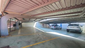 Ett underjordiskt parkeringsgarage med två parkerade bilar, betonggolv, tak av metall och en ingång med grind.