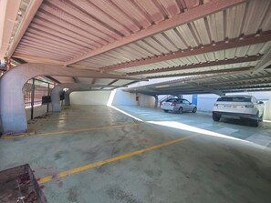 Eine Tiefgarage mit zwei Autos, Betonboden, Metalldecke und einem Durchgangstor.
