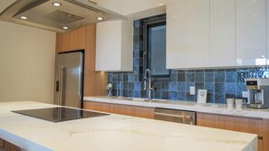 A modern kitchen with a built-in oven, a stainless steel refrigerator, a coffee machine, and a window above the sink. - Sunset Balcony | 3BR | 5-Min Drive to Eagle Beach (Noord)