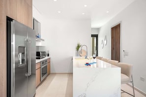 Eine moderne Küche mit Edelstahlgeräten, ein Essbereich mit Marmortisch und ein minimalistisches Design.