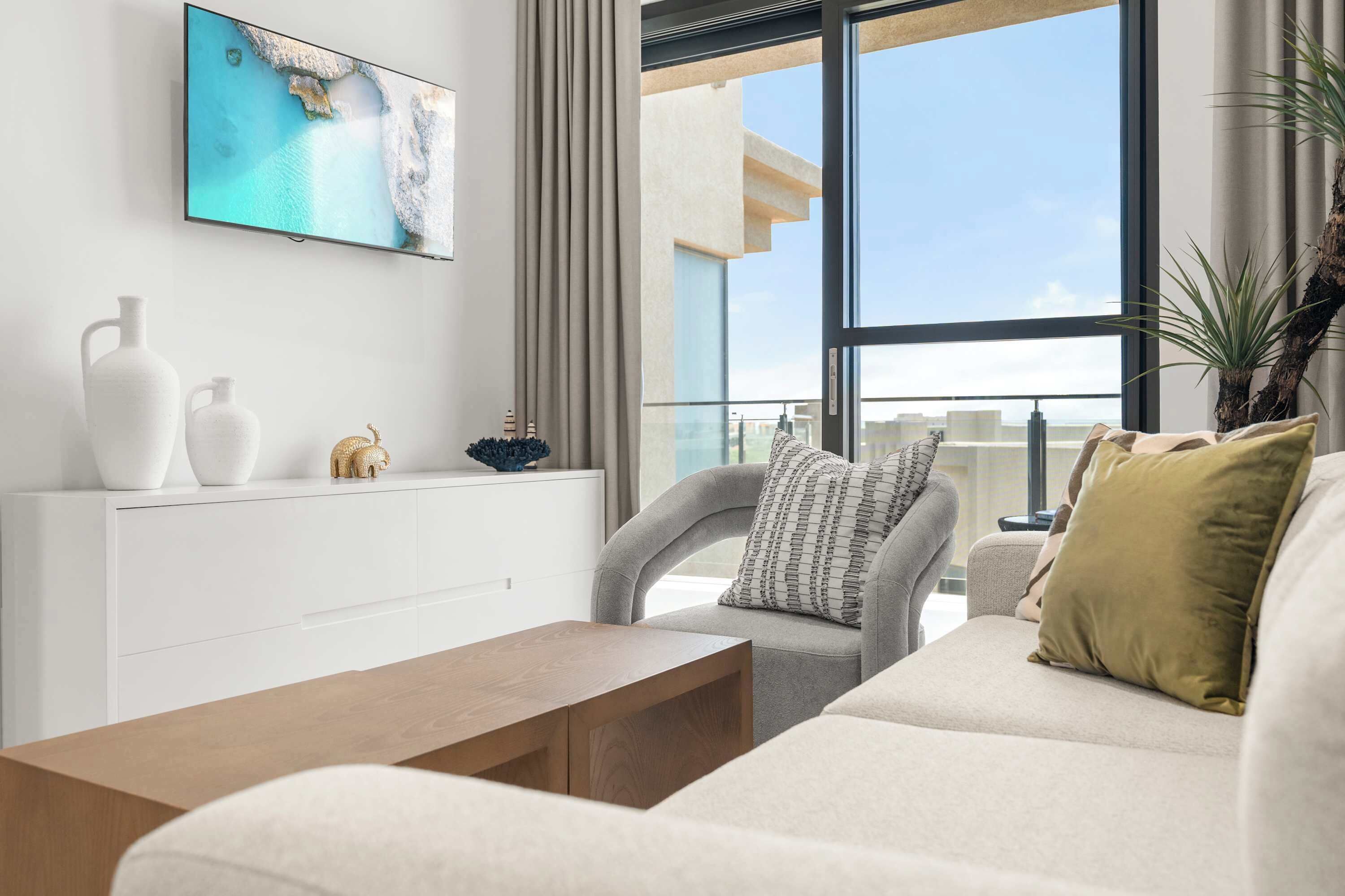 A modern living room with a sofa, a coffee table, and a TV mounted on the wall.