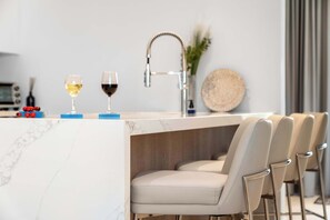 A modern kitchen with a marble countertop, a sink, and bar stools. - Near Eagle Beach| Top-Floor 1BR |Pool&Jacuzzi (Noord)