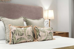 A bed with a headboard, two pillows, and a nightstand with a lamp. - Near Eagle Beach| Top-Floor 1BR |Pool&Jacuzzi (Noord)
