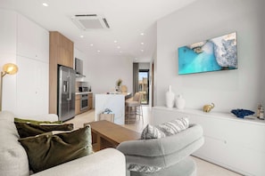 Un salon moderne avec un canapé, une table basse et un téléviseur fixé au mur.