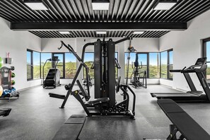A modern gym with various exercise equipment, large windows, and a view of the outdoors. - Near Eagle Beach| Top-Floor 1BR |Pool&Jacuzzi (Noord)