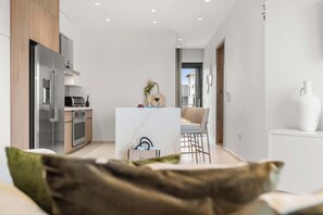 Une cuisine moderne dotée d’un îlot central, d’un coin repas avec un bar et d’une vue sur un bâtiment à l’extérieur.