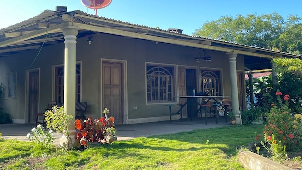 Una casa con porche, antena parabólica y mobiliario exterior.