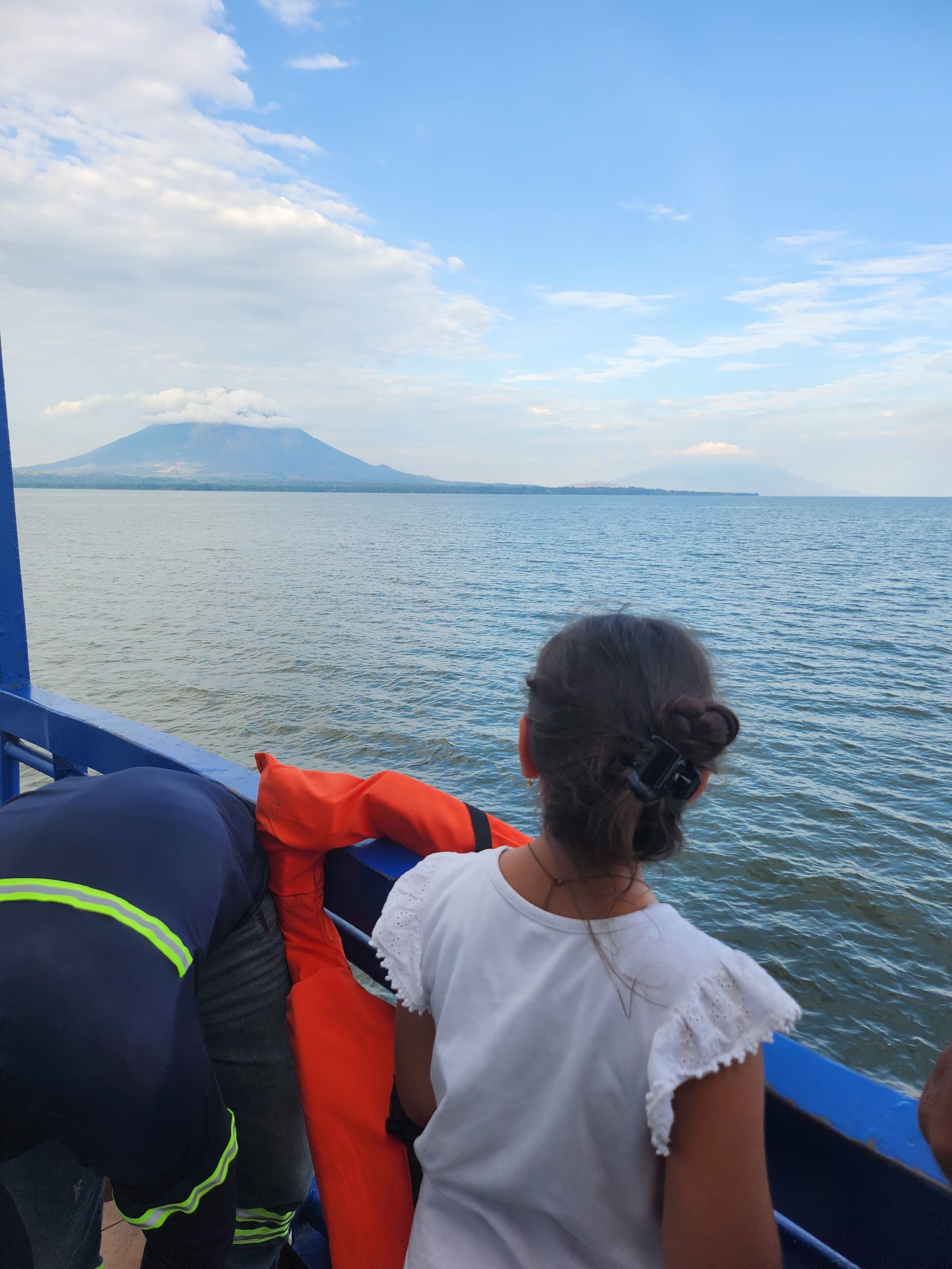 Una persona sentada en un bote, con vista a una montaña y al agua.