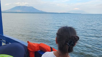 Una persona sentada en un bote, con vista a una montaña y al agua.