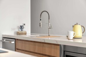 Eine moderne Küche mit einem Edelstahl-Wasserhahn, einer Kaffeemaschine und einer weißen Tasse auf der Arbeitsfläche.