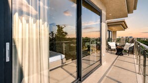 Un balcón con puerta de vidrio, una cama y mobiliario exterior.