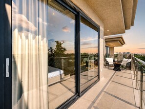 Ein Balkon mit Glastür, einem Bett und Gartenmöbeln.