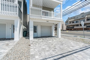 A residential building with a covered porch, two garages, and a paved driveway. - Luxury Jersey Shore Retreat Rooftop Oasis & Beach (Seaside Heights)