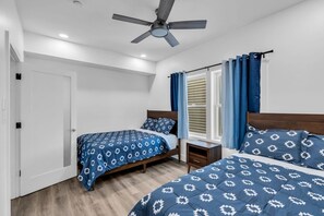A bedroom with two beds, a ceiling fan, a window with curtains, and a door. - Luxury Jersey Shore Retreat Rooftop Oasis & Beach (Seaside Heights)
