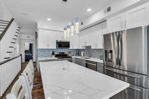 A modern kitchen with white cabinets, stainless steel appliances, and a marble island. - Luxury Jersey Shore Retreat Rooftop Oasis & Beach (Seaside Heights)