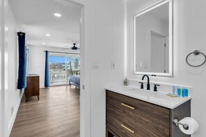 Un baño moderno con un espejo grande, un lavabo blanco y un mueble de tocador de madera.