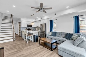 Una cocina moderna con armarios blancos, una isla central y una zona de comedor con sillas.