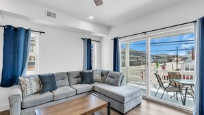 Een moderne woonkamer met een hoekbank, een salontafel en een grote schuifdeur naar een terras.