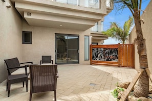 A patio area with wicker furniture, a glass door, and a wooden gate. - 5-Min Drive to Eagle Beach|Large Patio|Pool&Jacuzzi (Noord)