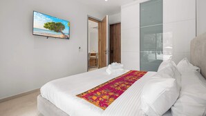 A modern bedroom with a large bed, a flat-screen TV, and a glass partition wall. - 5-Min Drive to Eagle Beach|Large Patio|Pool&Jacuzzi (Noord)