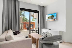 A modern living room with a sofa, armchair, and a TV mounted on the wall. - 5-Min Drive to Eagle Beach|Large Patio|Pool&Jacuzzi (Noord)