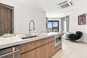 A modern kitchen with a central island, built-in oven, and stainless steel appliances. - Top-Floor 1BR | Resort Pool | Close to Eagle Beach (Noord)